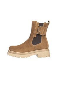 Bottes chelsea en suède brun avec panneaux élastiques, semelle plate crème et une sangle décorative avec des accents en métal sur le côté.