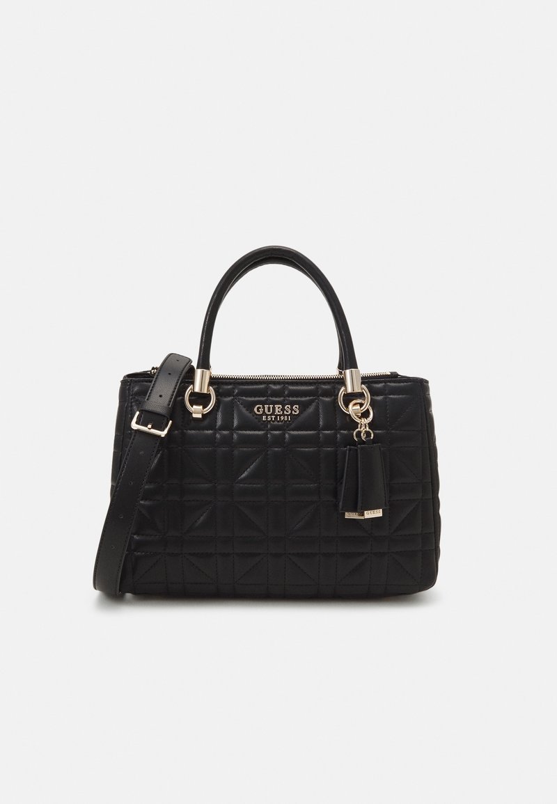 Sac à main matelassé noir Guess avec double poignée, ferrures dorées, bandoulière détachable et breloque pompon de marque.