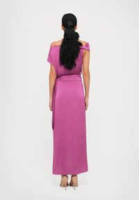 Off-shoulder, jurk tot de vloer van stevige magenta stof, met een getailleerde taille en zachte draping. Gladde textuur met een gestrikte accent aan de achterkant.