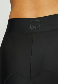 Leggings de desporto pretos com tecido suave e elástico, apresentando uma cintura larga e um detalhe de logotipo subtil perto do topo.