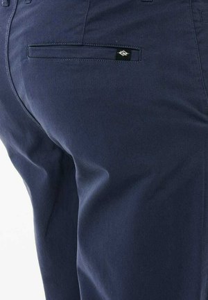 Navy blue trousers made of smooth cotton fabric, featuring a back pocket with a small black logo tag and subtle stitching details.