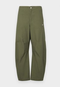 Calças largas em verde oliva com fecho de botão e discreto swoosh branco da Nike na coxa direita, exibidas sobre um fundo simples.