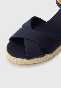 Marinblå canvas espadriller med korsade remmar, jute-mellansula och rund tå. Texturerad tyg och vävda detaljer framhäver designen.