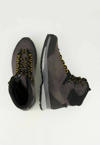 Scarpe da trekking con upper in suede grigio, accenti neri, lacci gialli e suole in gomma. Presentano un colletto imbottito per il supporto della caviglia.