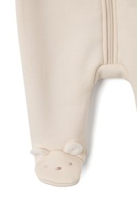 Bodi de color crema con una cremallera de longitud completa, con detalles de cara de oso en los pies y orejas suaves y esponjosas. Textura de tela suave.