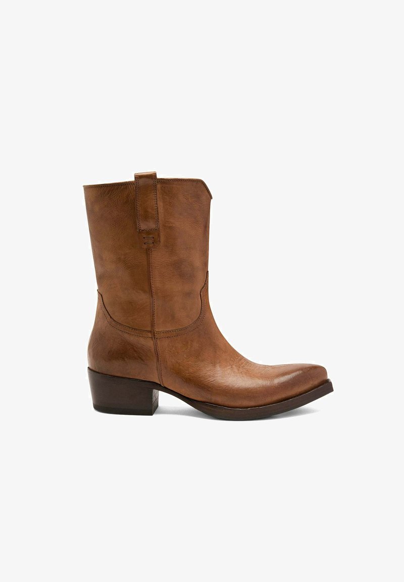 Bottine en cuir marron avec un bout légèrement pointu, un petit talon carré et une languette ; texture lisse avec des détails de couture subtils.