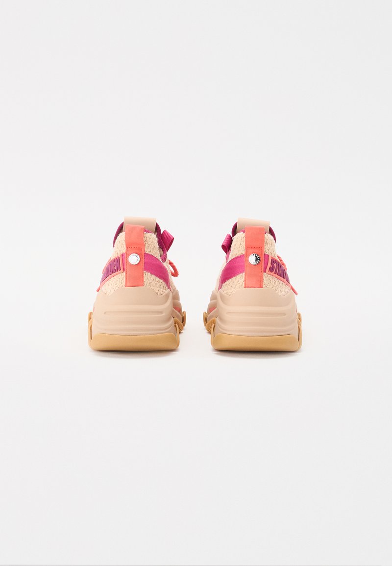 Schoen met een beige mesh bovenwerk, roze en oranje banden, en een gele rubberen zool. Bevat een cirkelvormig logo en gestikte accenten.