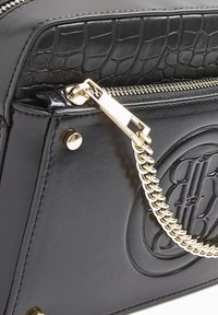 Svart läderhandväska med ett krokodilpräglat panel, guldfärgad hårdvara, flätad kedjerem och en dragkedjestängning.