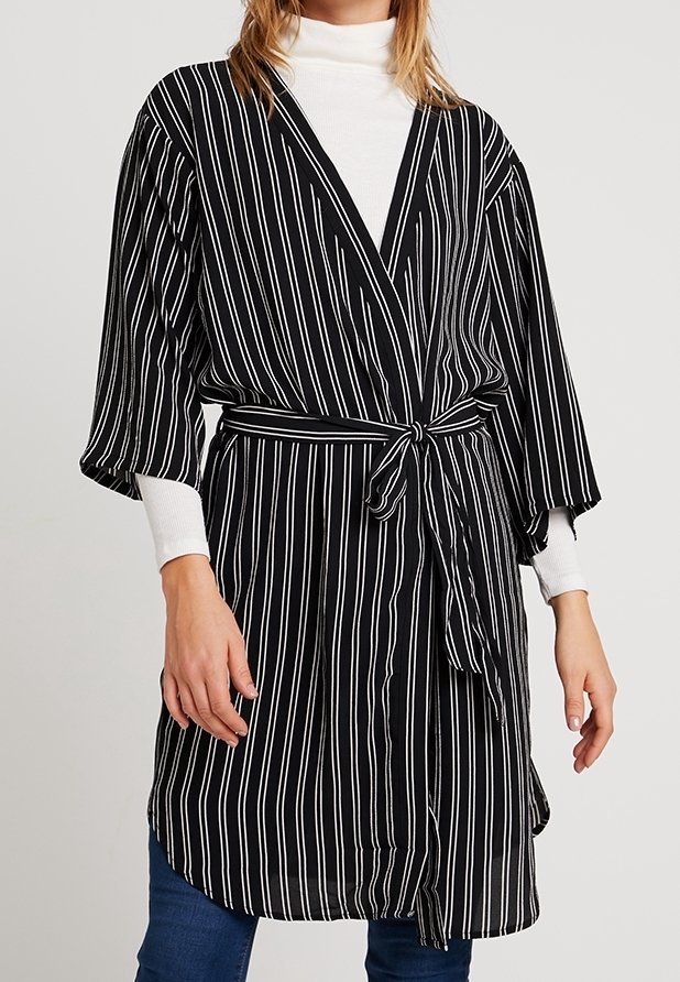Robe portefeuille style kimono à rayures verticales noires et blanches, manches longues, taille ceinturée et tissu léger.