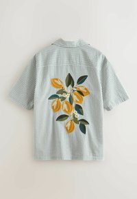 Koszula z krótkim rękawem w jasnoszare paski z haftowanymi żółtymi cytrynami i zielonymi liśćmi na plecach.