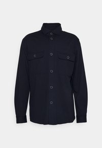 Svart långärmad skjorta med knappar och krage, utrustad med två bröstfickor, var och en med locket fäst med en knapp.