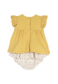 Robe jaune en coton avec motif texturé, manches à volants et fermeture à boutons ; superposée à un bas beige imprimé floral.