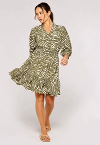 Grünes, zebra gestreiftes Kleid mit V-Ausschnitt, langen Ärmeln und einem gestuften Volantsaum. Hergestellt aus leichtem Stoff, mit einem elastischen Taillenbund.