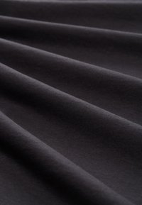 Schwarzer Stoff mit einer glatten Textur, der sanfte Falten und einen leichten Glanz zeigt und ein leichtes, elastisches Material präsentiert.