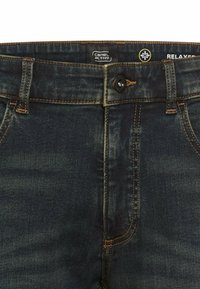 Dark blue denim jeans with a relaxed fit, featuring a front button closure, orange stitching accents, and a branded waistband label.
