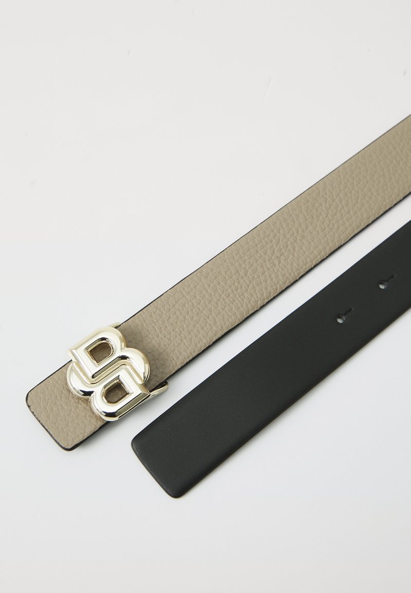 Dos correas de cinturón: una de cuero beige texturizado con una hebilla plateada en forma de doble "B", y otra de cuero negro liso con agujeros para ajustes.