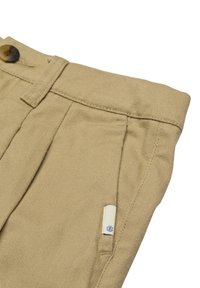 Beige, tilspidsede bukser lavet af et tekstureret stof, med en frontplisse, knaplukning og et lille logomærke på lommen.