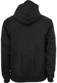 Black hooded jacket made of shiny, lightweight material, featuring a smooth texture, elastic cuffs, and a ribbed hem.
