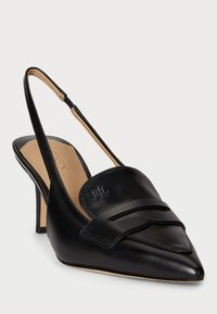 Crne kožne cipele s remenom oko pete i šiljastim vrhom s dekorativnom trakicom. Imaju malu petu i vidljivo brendiranje sprijeda.