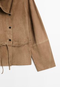 Veste longue en daim marron avec des boutons noirs sur le devant et une fine ceinture nouée à la taille.