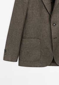 Blazer da uomo con motivo pied de poule marrone e beige, polso con bottoni, tasca frontale e un unico bottone nero visibile sulla chiusura anteriore.
