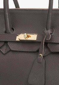 Donkerbruine leren handtas met een gestructureerd oppervlak, gouden sluiting en decoratieve accenten. Inclusief een label zonder zichtbare tekst.