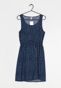 Granatowa sukienka bez rękawów w białe kwiaty, zgromadzona w talii, gładki materiał i okrągły dekolt, wisząca na czarnym haczyku.