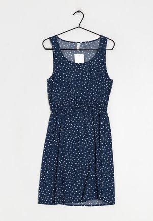 Vestido sin mangas de color azul marino con un patrón floral blanco, fruncido en la cintura, de tejido suave y con un escote redondo, colgando de un gancho negro.