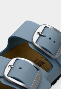 Γαλάζια σανδάλια με δύο ρυθμιζόμενους ιμάντες με ασημένιες αγκράφες, λείο υλικό και καφέ πάτο για άνεση.