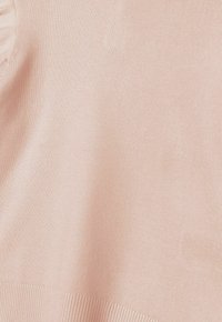 Top lavorato a maglia di colore rosa delicato con una texture sottile, caratterizzato da un orlo a costine. Il materiale sembra morbido, leggero e leggermente riflettente.