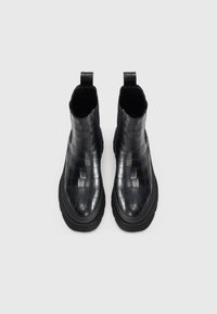 Black leather ankle boots with a woven pattern, featuring a rounded toe and thick rubber sole. Pull tabs are located at the back.