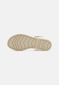 Semelle d'une chaussure, dotée d'un matériau en caoutchouc beige avec une surface texturée et un motif en zigzag pour une meilleure adhérence. Marquée de la taille 37.
