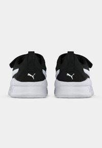 Chaussures de sport noir et blanc avec une tige en tissu doux, une semelle épaisse et un logo distinctif à l'arrière. Équipées de languettes de tirage pour un enfilage facile.