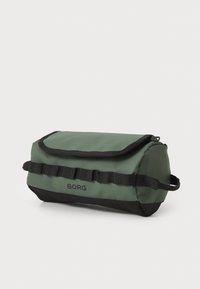 Zeleni i crni pravokutni putni okvir s preklopom, izrađen od izdržljive tkanine. Sadrži logo, bočnu ručku i teksturirani dizajn trake.