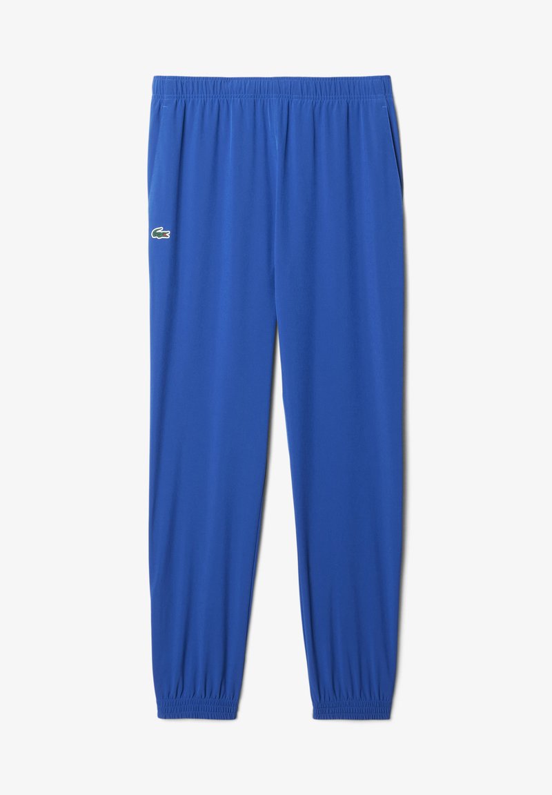 Blaue Sporthose mit elastischem Bund und Bündchen, seitlichen Taschen und einem kleinen grünen Krokodil-Logo auf dem linken Oberschenkel.