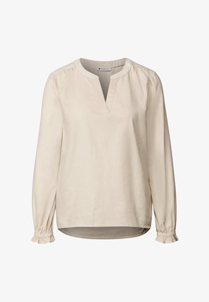 Beżowa bluzka z długim rękawem, z dekoltem w kształcie litery V i marszczonymi ramionami. Posiada bufiaste mankiety oraz gładki, teksturowany materiał. Dół jest lekko zaokrąglony.
