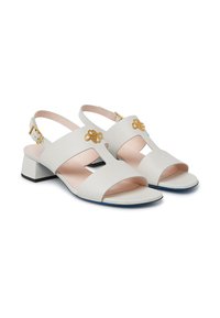Sandali slingback in pelle bianca con tacco a blocco, caratterizzati da un design a intaglio, dettagli dorati e una soletta rosa chiaro.