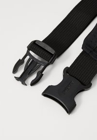 Cinghia in nylon nera con doppi fibbie in plastica. Superficie strutturata con una fibbia che presenta un design a gancio e l'altra è piatta e larga.