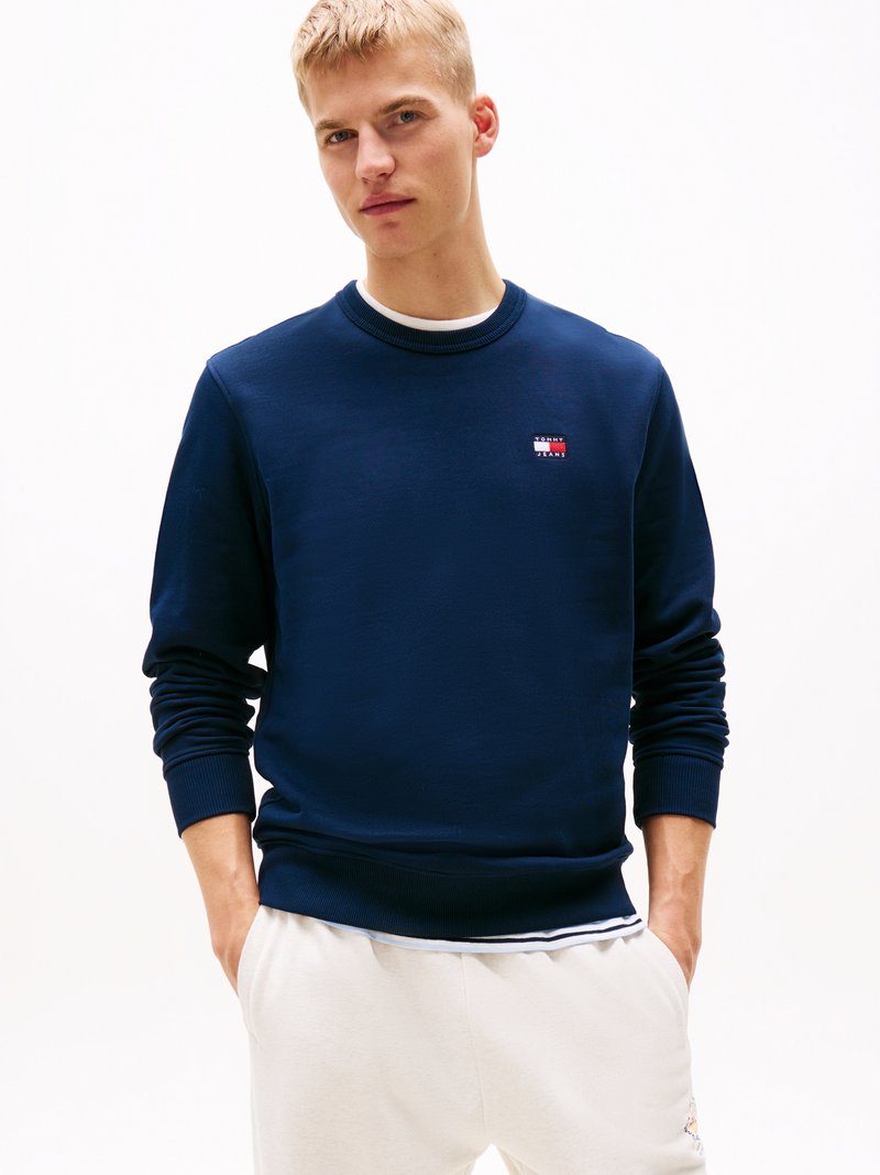 Sweatshirt azul em mistura de algodão, com punhos e gola canelados, apresentando um pequeno emblema no peito. Corte casual.