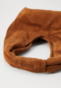 Brown suede handbag with a soft texture, rounded shape, and a prominent "BRONX" embossed logo on the handle. No visible hardware details.