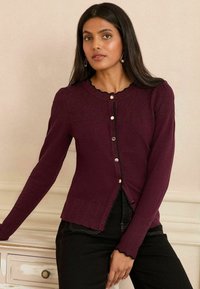 Burgunský pletený cardigan s dlouhými rukávy, vroubkovaným výstřihem, strukturovaným trupem, pěti zlatými knoflíky a rovnou spodní částí s vroubkovanými okraji.