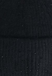 Berretto di lana nera a maglia con texture a coste, caratterizzato da piccoli pois decorativi in rilievo su tutta la superficie. Materiale morbido e flessibile.