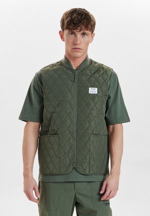 Olive green quilted vest with a zip front, round collar, two front pockets, paired with a short-sleeved dark green shirt underneath.