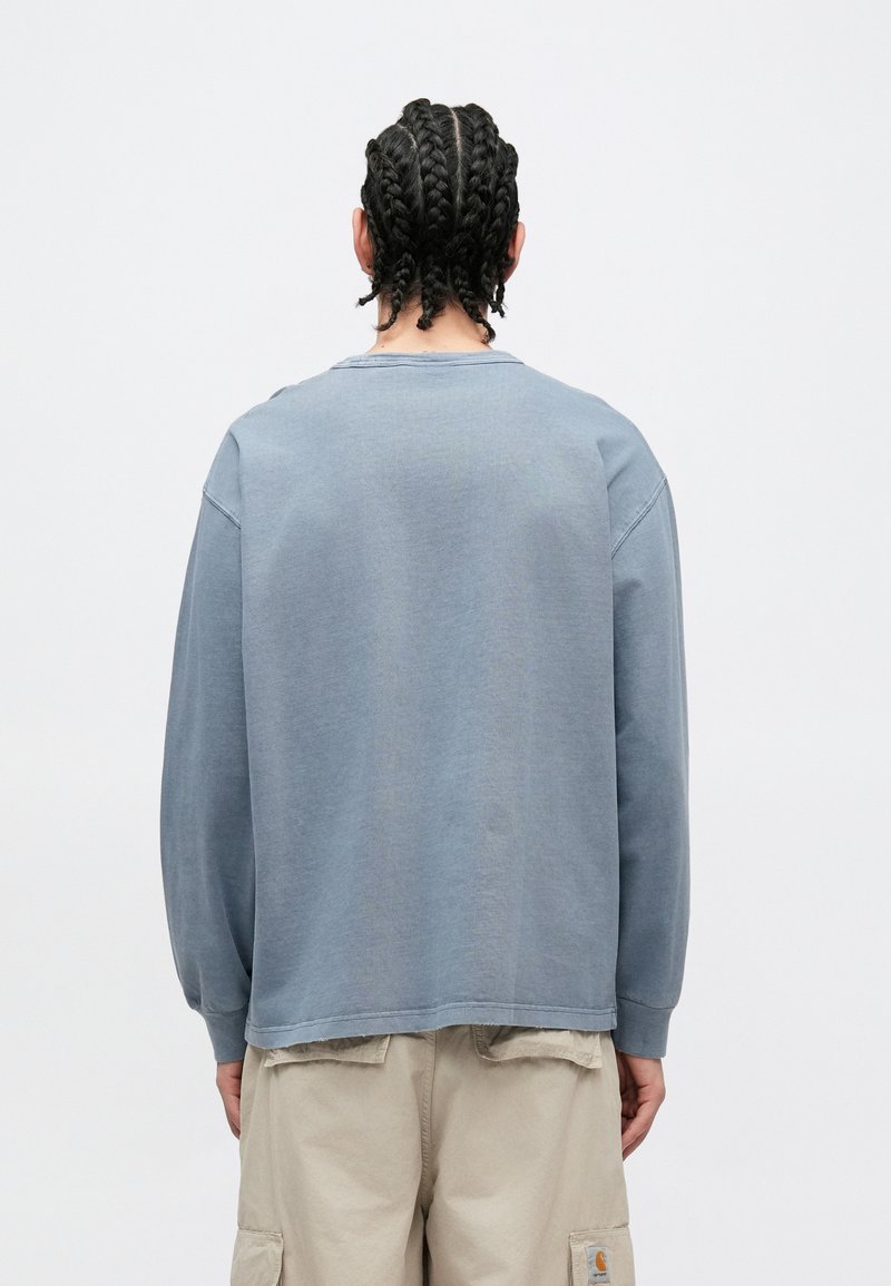 Ljusblå sweatshirt med långa ärmar, rund halsringning och en avslappnad passform. Tillverkad av mjuk bomull med synliga sömndetaljer på baksidan.