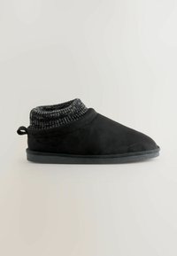 Sort slippers med en tekstureret strikket krave, suede-lignende ydre, rund tå og flad gummisål. Løkke bagpå for nem påtagning.