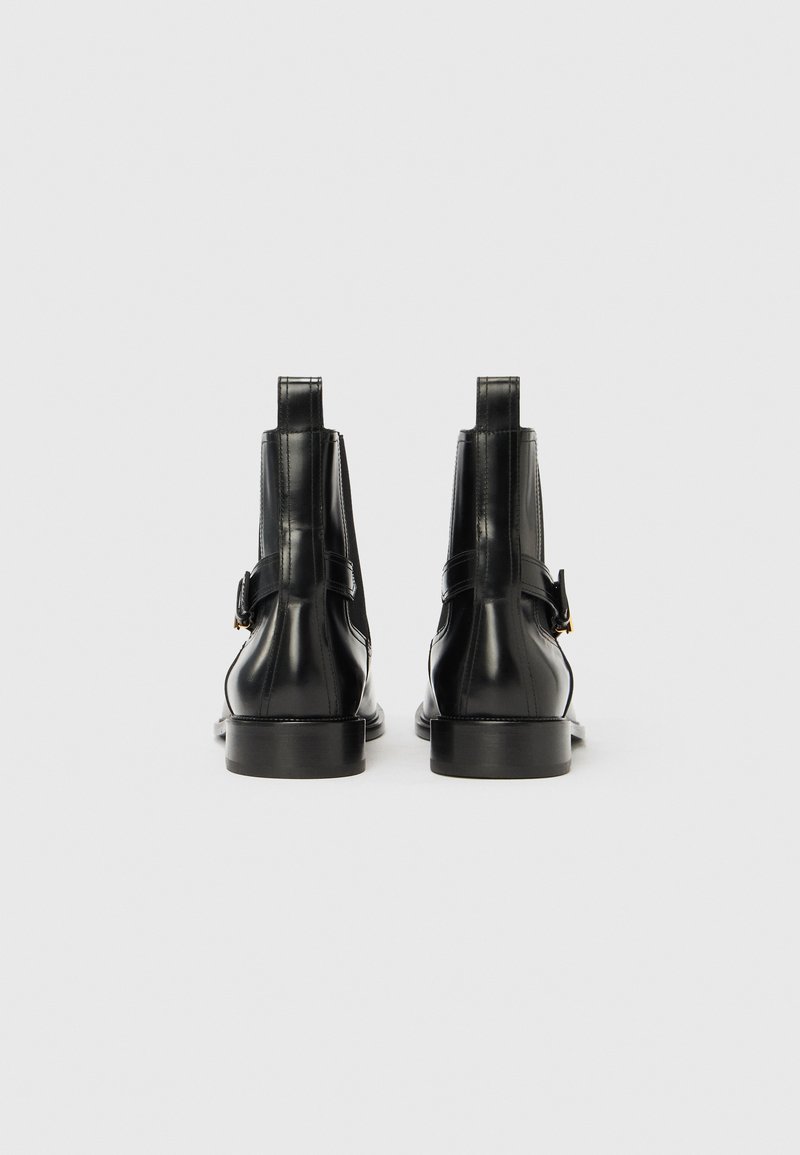 Sorte ankelstøvler i læder med en glat finish, der har en sidespænde med strop, rundet tå og lav, robust hæl.