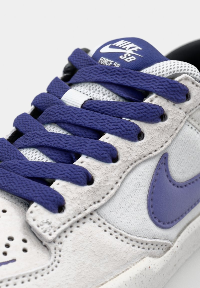 Nike SB Sneakers in Weiß und Lila. Besteht aus Wildleder und Mesh-Materialien, flachen lila Schnürsenkeln und einem Logo auf der Zunge. Abgerundete Zehenform.