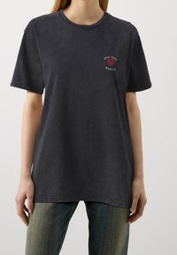 Tmavě šedé tričko s krátkým rukávem, kulatým výstřihem, vybledlou texturou, s vyšitým vzorem růže a textem na levé části hrudi.