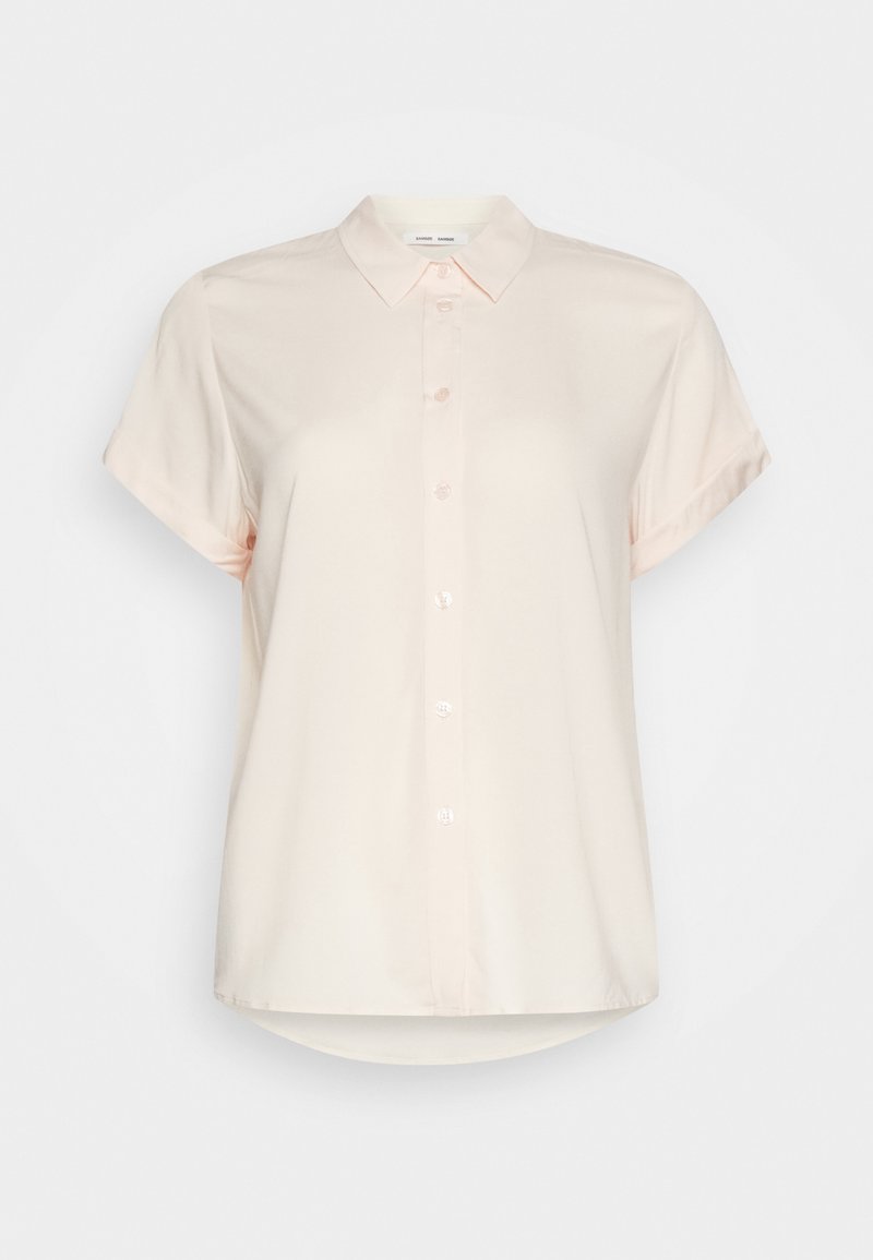 Chemise beige clair à manches courtes avec une patte de boutonnage devant, un col et un bas légèrement arrondi. Tissu lisse avec une subtile brillance.