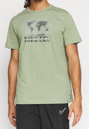 Camiseta de algodón en verde oliva con un gráfico de un globo y el texto "NIKE F.C." en blanco y negro, con cuello redondo y mangas cortas.